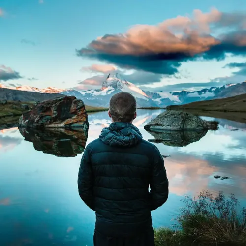man looking out over lake with reflective surface